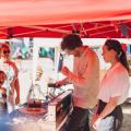 Marekt scene with visitors, Thomas and Sa at the exhibition stand on a sunny day.