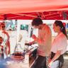 Marekt scene with visitors, Thomas and Sa at the exhibition stand on a sunny day.