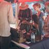 Scene with market visitors and Thomas at the exhibition stand on a sunny day.